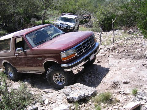1996 Ford Bronco - 1996 Ford Bronco tackling an off-road trail, with another vehicle following.