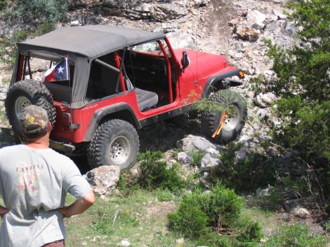 1996 Ford Bronco - A red Jeep Wrangler is positioned on a rocky incline, with a person observing from the foreground.