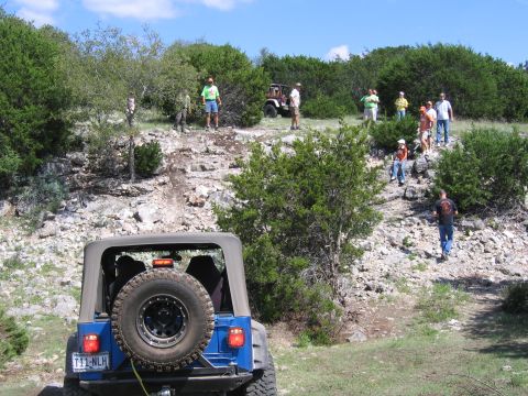 1996 Ford Bronco - Off-roading group with multiple Jeeps on a rocky trail under a blue sky.