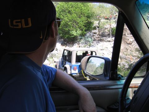 1996 Ford Bronco - Two Jeeps navigate a , off-road trail under a bright sky.