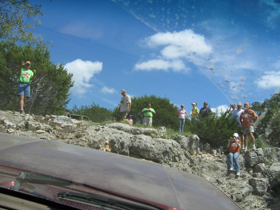 People gathered on a rocky hill under a blue sky
