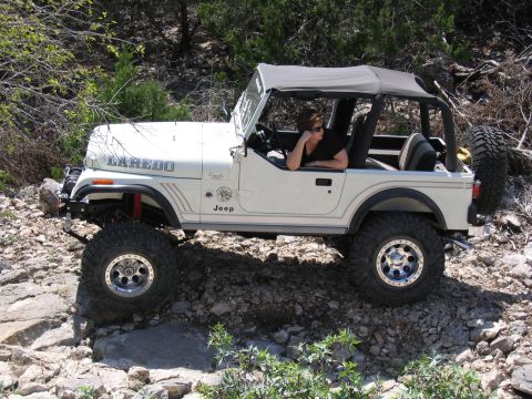 1996 Ford Bronco - A white Jeep CJ Laredo navigates a rocky off-road path with a woman in the driver's seat.