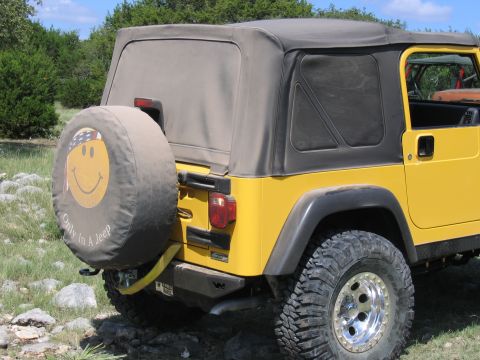 1996 Ford Bronco - A yellow Jeep Wrangler is parked outdoors on a rocky surface with trees in the background.