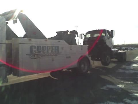 1992 Ford Bronco - A tow truck is hauling a cab-over truck chassis on a bright, overcast day.