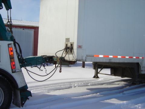 1992 Ford Bronco - A tow truck is connected to a trailer in a snowy environment.