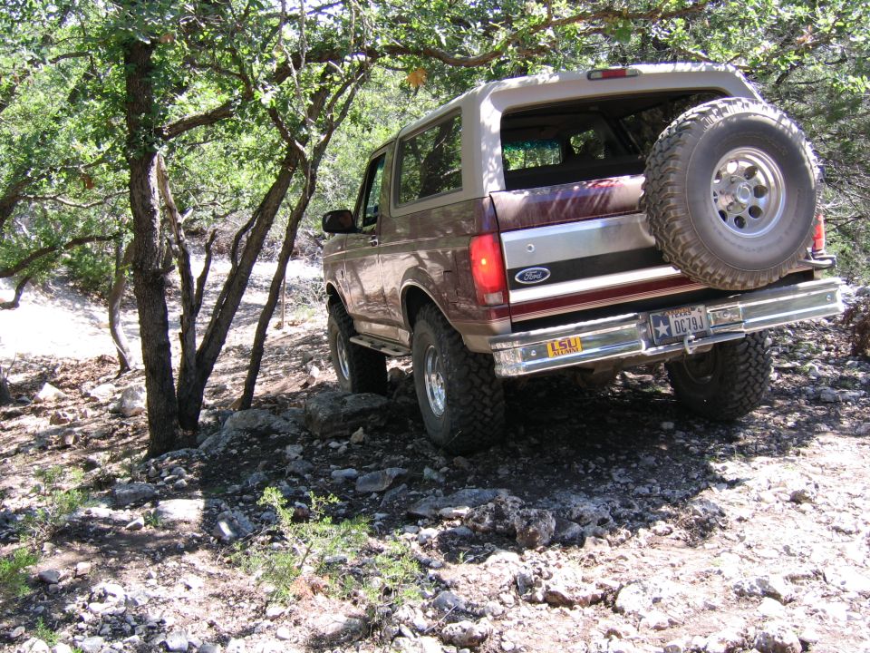 Brown 1996 Ford Bronco on rocky trail, spare tire on back