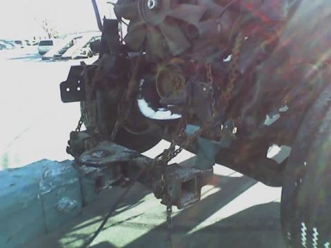 1992 Ford Bronco - This photo shows the engine and chassis of a vehicle, heavily rusted and secured with chains.