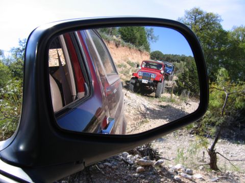 1996 Ford Bronco - A convoy of Jeeps navigates a rocky trail, seen through the reflection of a side mirror.
