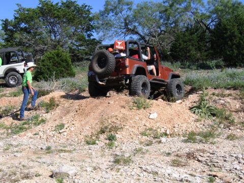 1996 Ford Bronco - Two Jeeps navigate a rocky, off-road trail under a clear blue sky.