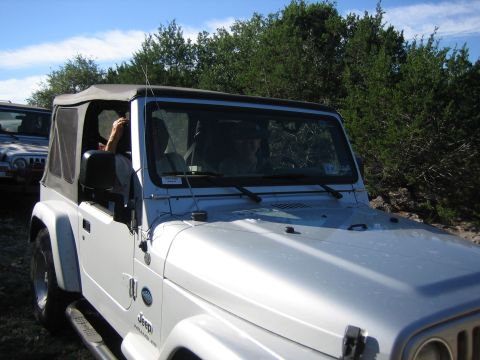 1996 Ford Bronco - Two Jeep Wranglers on a dirt road with trees in the background.