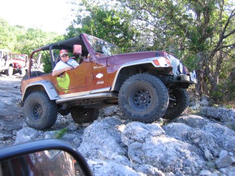 1996 Ford Bronco - A driver navigates a Jeep Wrangler over a challenging rocky terrain during an off-road excursion.