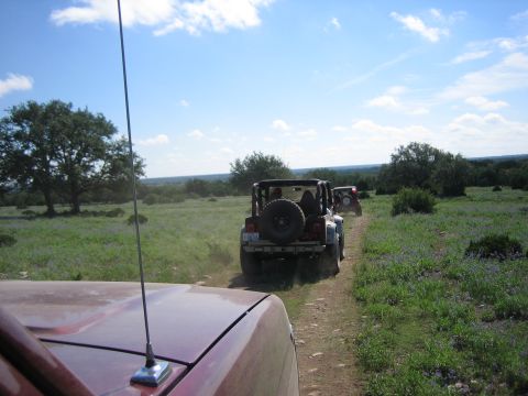 1996 Ford Bronco - A convoy of Jeeps travels down a dusty trail in a rural landscape.