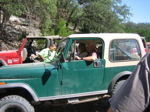 1996 Ford Bronco - Two Jeeps are parked side-by-side on a dirt road with trees in the background.