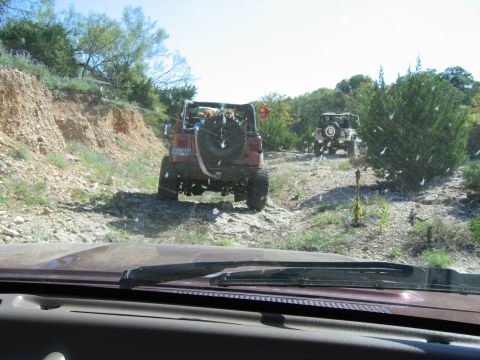 1996 Ford Bronco - Two off-road vehicles navigate a challenging rocky trail under a clear blue sky.
