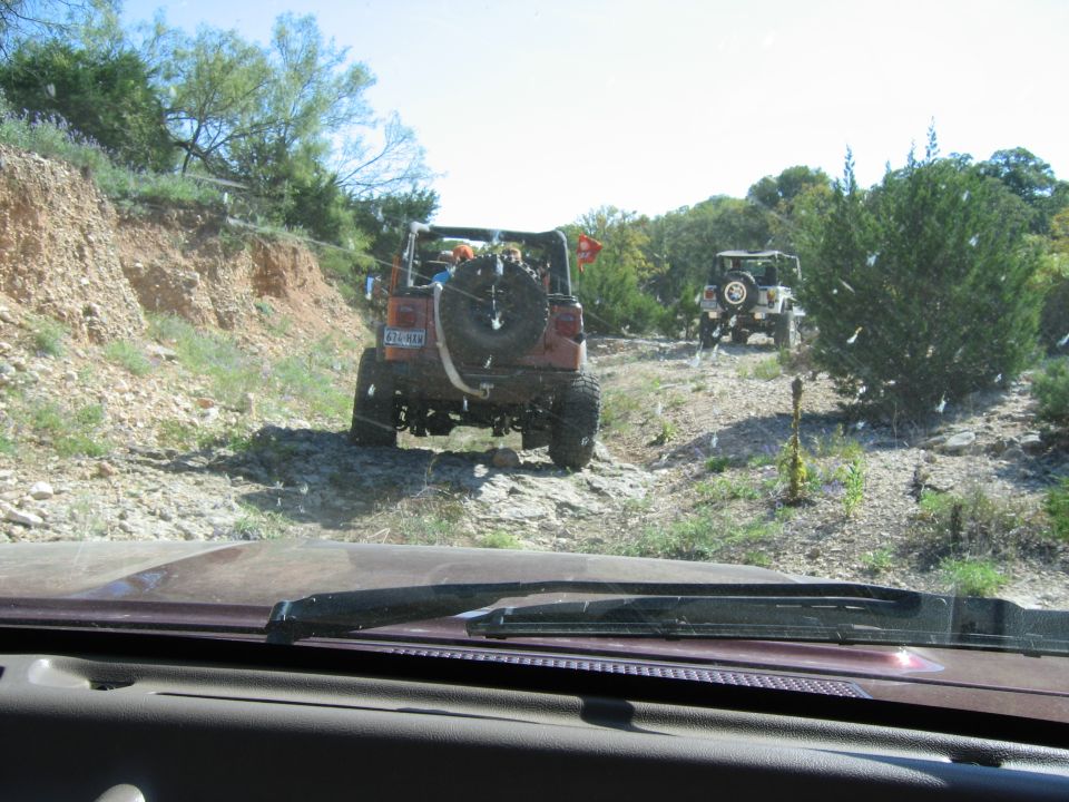 Two off-road vehicles on a rocky trail, one red and one white