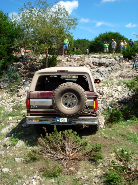 1996 Ford Bronco - A Ford Bronco navigates a rocky off-road course with spectators observing from the surrounding terrain.