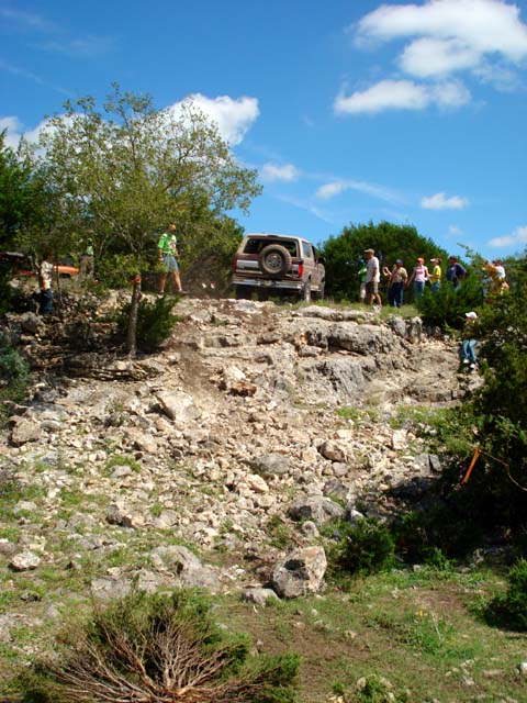1996 Ford Bronco - A Ford Bronco navigates a challenging rocky incline with spectators watching.