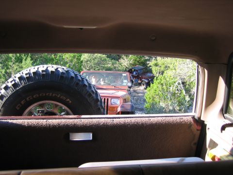 1996 Ford Bronco - View from inside a vehicle shows two Jeeps driving on a wooded dirt road.