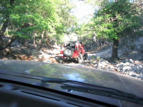 1996 Ford Bronco - Two vehicles navigating a rough, rocky path through a wooded area.