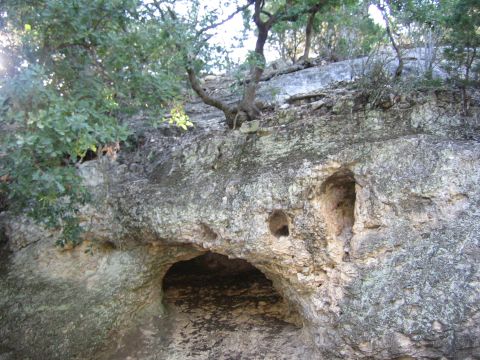 1996 Ford Bronco - Natural rock formations with caves and trees on a hillside.
