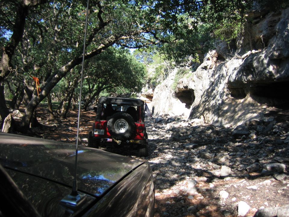 Red Jeep Wrangler on a rocky trail with a second vehicle in the foreground