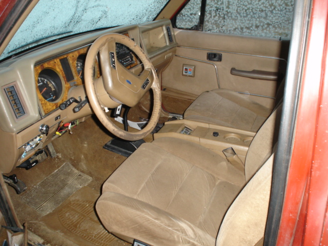 Tan interior of a 1980s SUV, showing dashboard, steering wheel, and seats