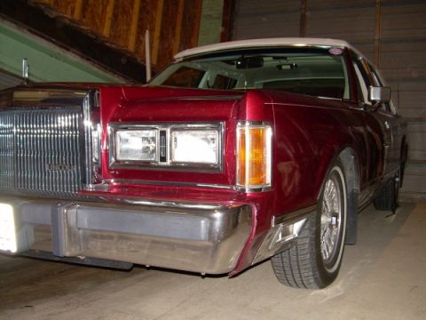 1989 Lincoln Town Car - The front end of a red 1989 Lincoln Town Car is shown, a prominent chrome grille and dual rectangular headlights.