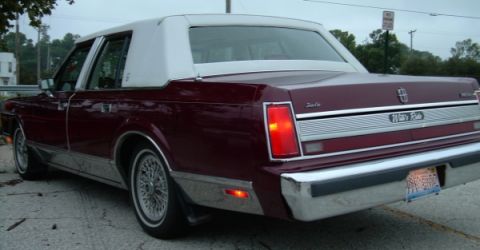 1989 Lincoln Town Car - Rear 3/4 view of a maroon 1989 Lincoln Town Car with a white vinyl roof. The 'Town Car' and 'Wellesley' badges are visible on the trunk lid.