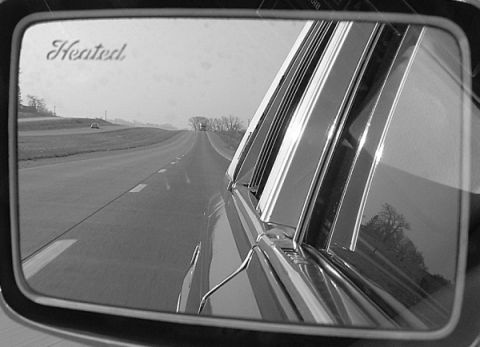 1989 Lincoln Town Car - A view of the open road reflected in a car's side mirror, with a distant vehicle visible.