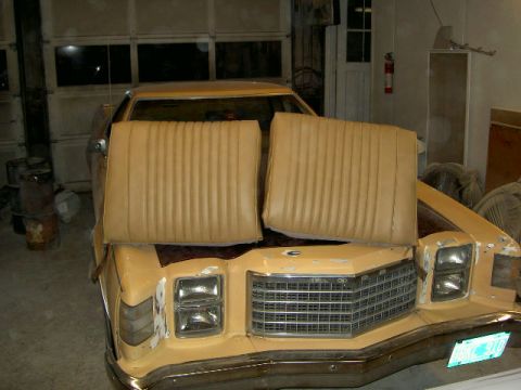1967 Ford Ranchero - Two tan bucket seats are placed on the hood of a yellow vehicle, obscuring the grille and front end.