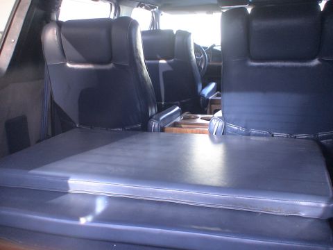 1993 Ford C-350 (Centurion Conversions) - Interior of a van showing multiple rows of dark blue seats and a fold-out bed in the foreground.