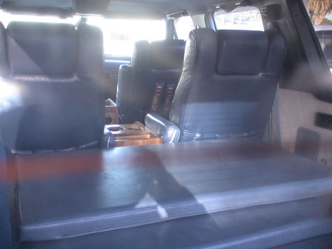 1993 Ford C-350 (Centurion Conversions) - Interior view of a van's seating area, dark leather seats and a wooden console.