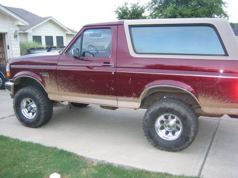 1996 Ford Bronco - This maroon Ford Bronco is parked on a concrete driveway and appears to have recently been off-roading.