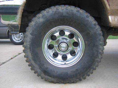 1996 Ford Bronco - A close-up view of a off-road tire and shiny chrome wheel on a vehicle.