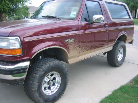 1996 Ford Bronco - A muddy 1996 Ford Bronco is parked on a concrete driveway.