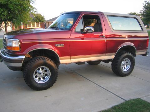 1996 Ford Bronco - This red Ford Bronco features a tan removable top and appears to be from the early to mid-1990s.