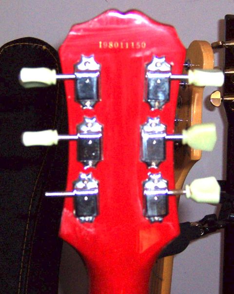 1978 Ford Bronco - Close-up of a red guitar headstock showing tuning pegs and a serial number.