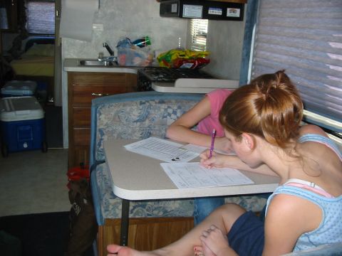 1996 Ford Bronco - Two people are seated at a table inside an RV, one of them is writing on a document.