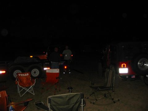 1996 Ford Bronco - Nighttime scene with people, a trailer, and a red SUV, camping chairs are set up.
