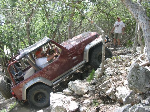 1996 Ford Bronco - A red Jeep Wrangler tackles a challenging off-road course, demonstrating its capability on rough terrain.
