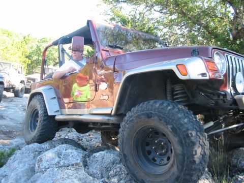 1996 Ford Bronco - A man drives a maroon Jeep Wrangler over a rocky trail, with another Jeep following behind.