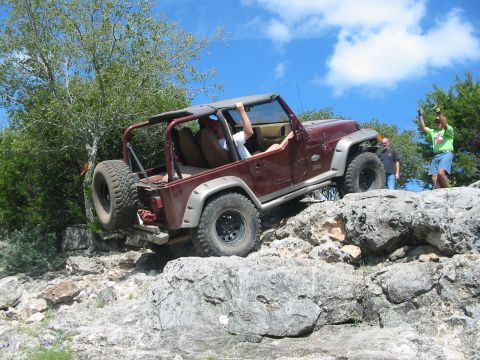 1996 Ford Bronco - Jeep Wrangler TJ navigating a rocky trail with spectators watching.