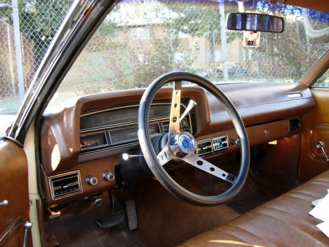 1970 Ford Ranchero - The interior of a 1970 Ford Ranchero features a brown dashboard, steering wheel, and bench seat.