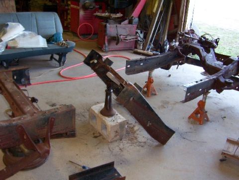 1992 Lincoln Custom - Multiple vehicle frames are disassembled and supported by jack stands in a workshop environment.