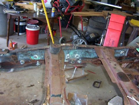 1992 Lincoln Custom - Close-up of a heavily rusted vehicle frame, showing bolts and suspension components.