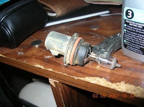 1991 Ford F-150 - A Sylvania headlight bulb sits on a wooden table next to a black pouch and a bottle with instructions.
