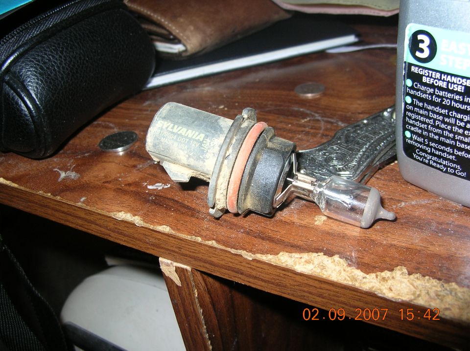 Sylvania 9004 headlight bulb in its socket on a wooden shelf
