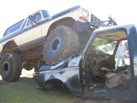 1992 Ford Mustang - A lifted Ford Bronco is perched atop a heavily modified pickup truck cab, displaying "Bronco 4x4" badging.