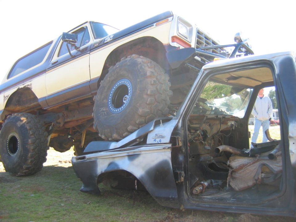 Yellow and black Ford Bronco on top of a pickup truck cab. "Bronco 4x4" badge visible