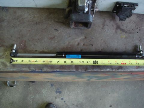 1996 Ford Bronco - A gas strut is shown with a measuring tape, indicating its length. The registry claims it is from a 1996 Ford Bronco, but this is unconfirm…